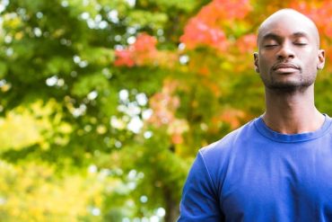 Homem praticando yoga em um ambiente sereno, com foco na postura e meditação, representando o curso Yoga para Iniciantes BTFIT.