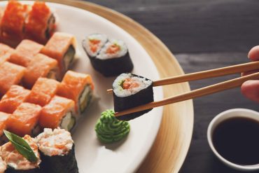 Estudante focada aprendendo a fazer sushi no Curso de Culinária Japonesa IPED