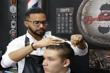 Barbeiro profissional cortando cabelo masculino com precisão em barbearia moderna